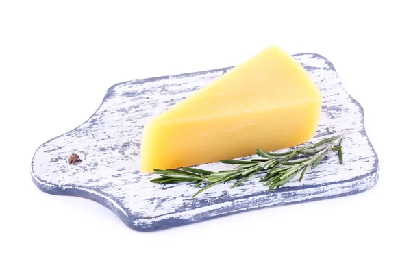 Chunk of Parmesan cheese on wooden cutting board with sprig of rosemary isolated on white — Stock Photo, Image