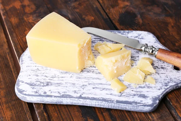 Parmesan cheese on cutting board with knife on wooden table background — Stock Photo, Image