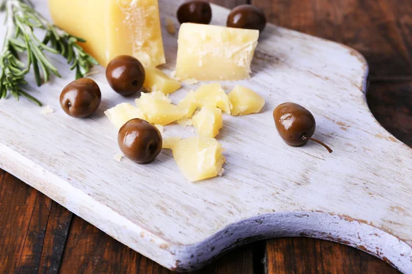 Пармезанський сир на обробній дошці з гілочкою розмарину та оливками на дерев'яному столі фоні — стокове фото