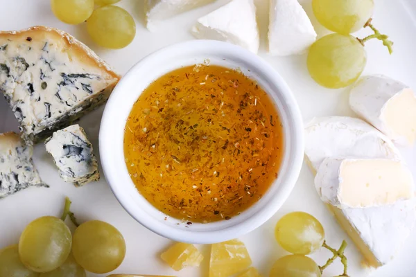 Diferentes tipos de queijo com uva e pires no prato, close-up — Fotografia de Stock