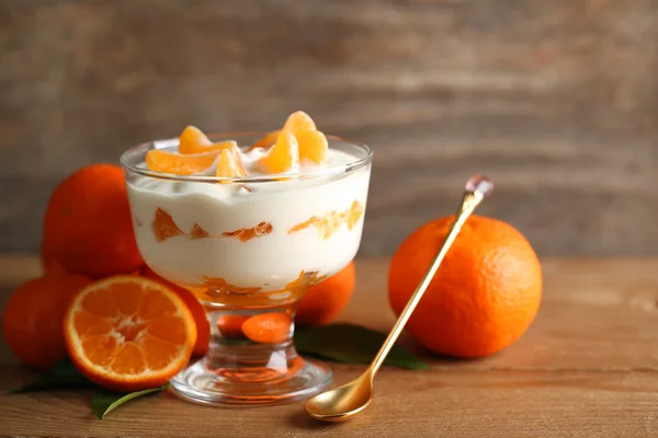 Dessert au lait savoureux avec des morceaux de mandarine frais dans un bol en verre, sur fond en bois — Photo