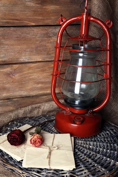 Lampe au kérosène avec rose séchée et lettre sur toile d'osier et planches de bois fond — Photo