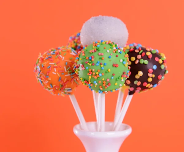 Söta cake pops i vas på orange bakgrund — Stockfoto