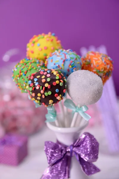 Sweet cake pops in vase on table on purple background — Stock Photo, Image