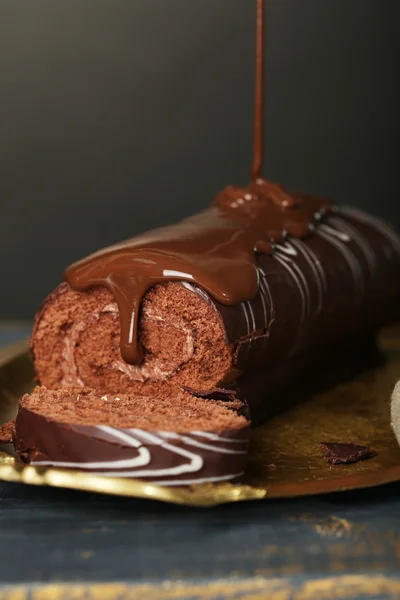 Délicieux gâteau roulé sur table en bois, sur fond sombre — Photo