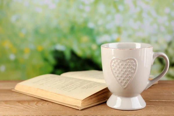 Taza de té y libro en la mesa, sobre fondo brillante —  Fotos de Stock