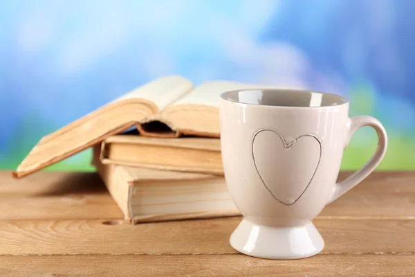 Xícara de chá e livros na mesa, no fundo brilhante — Fotografia de Stock
