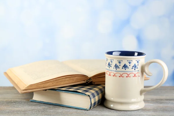 Taza de té y libros sobre la mesa, sobre fondo brillante —  Fotos de Stock