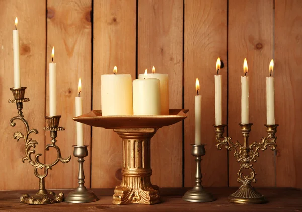 Retro candlesticks with candles on wooden background — Stock Photo, Image