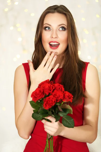 Ragazza sorridente con mazzo di rose rosse su sfondo luci — Foto Stock