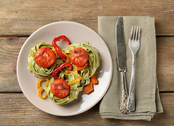 Pâtes vertes savoureuses au poivre et tomates sur fond de table en bois — Photo