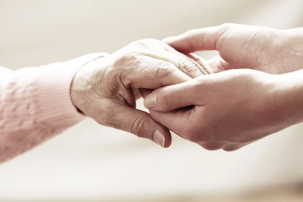 Old and young holding hands on light background, closeup Stock Image