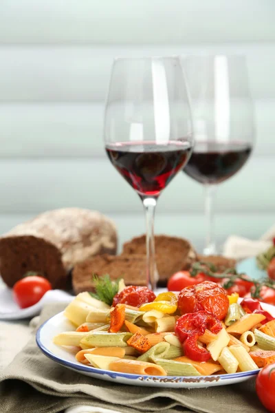 Ensalada de pasta con verduras y dos copas de vino tinto sobre fondo de mesa de madera — Foto de Stock