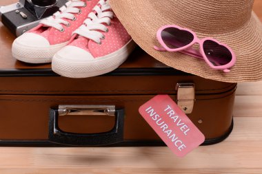 Ahşap arka plan üzerinde yazıt seyahat sigortası ile bavul ve turistik şeyler
