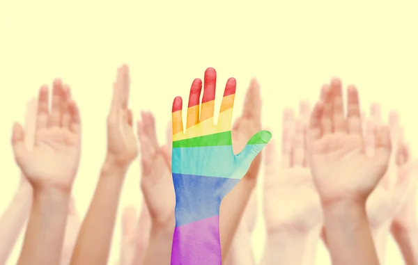 Las manos del hombre pintadas como la bandera del arco iris en el fondo de otras manos aisladas en blanco — Foto de Stock