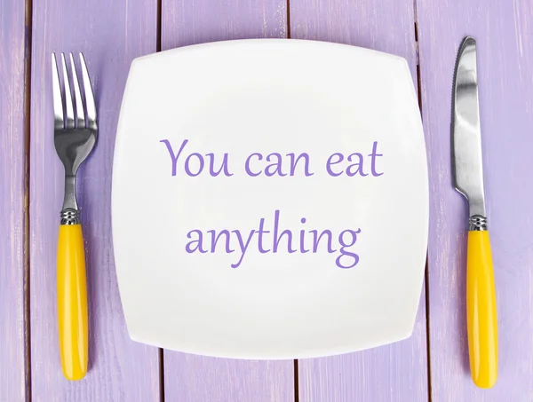 Lemez szöveg "Lehet enni bármit", Villa és kés, fából készült háttér — Stock Fotó