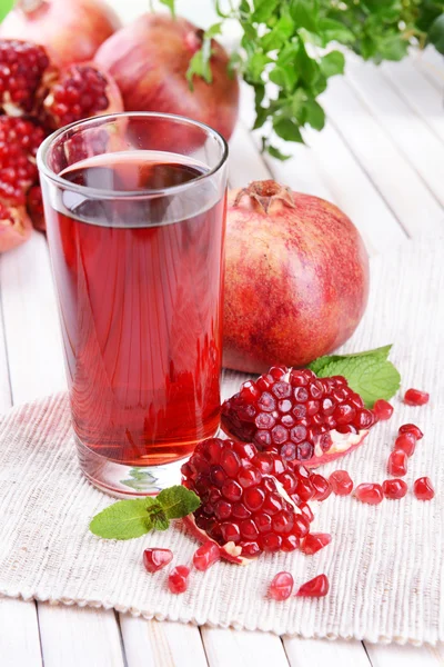 Reife Granatäpfel mit Saft auf dem Tisch vor hellem Hintergrund — Stockfoto