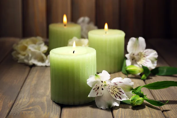 Mooie kaarsen met bloemen op houten achtergrond — Stockfoto