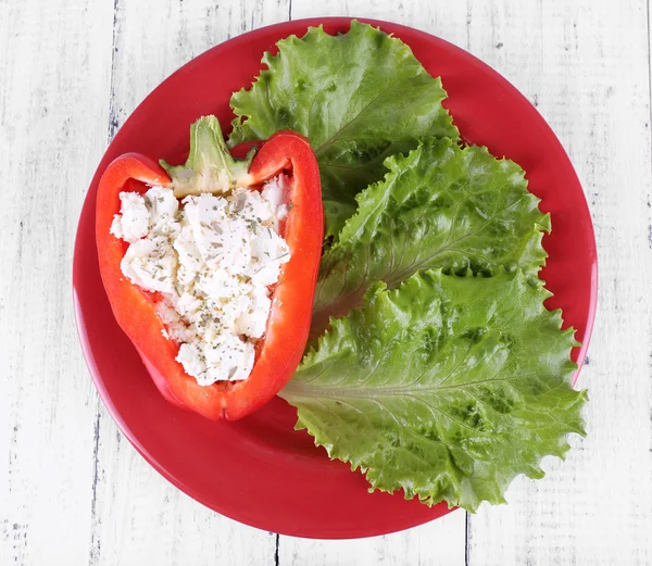 Stuffed pepper and lettuce on plate on wooden background — Stock Photo, Image