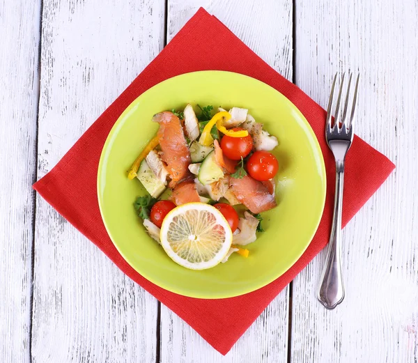 Fresh fish salad with vegetables on plate on wooden table close-up — Stock Photo, Image