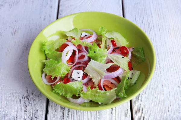 Fresh fish salad with vegetables on plate on wooden table close-up — Stock Photo, Image