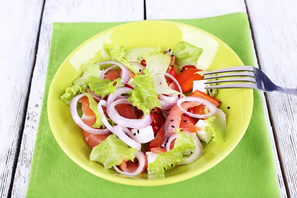 Frischer Fischsalat mit Gemüse auf Teller auf Holztisch in Großaufnahme — Stockfoto