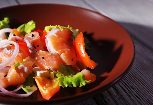 Färsk fisk sallad med grönsaker på tallriken på träbord närbild — Stockfoto