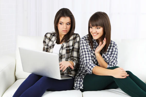 Schöne Mädchen Zwillinge sitzen auf Sofa mit Notizbuch — Stockfoto