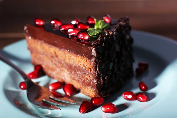 Köstlicher Schokoladenkuchen mit Granatapfelkernen auf dem Teller auf dem Tisch — Stockfoto