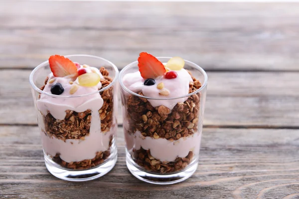 Здоровый многослойный десерт с мюсли и ягодами на столе — стоковое фото