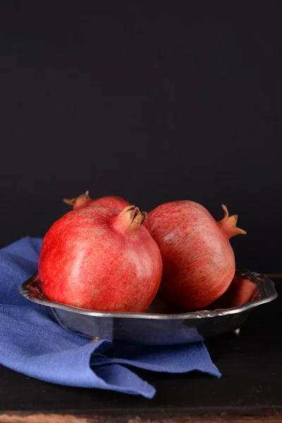 Juicy ripe pomegranates on wooden table, on dark background — Stock Photo, Image