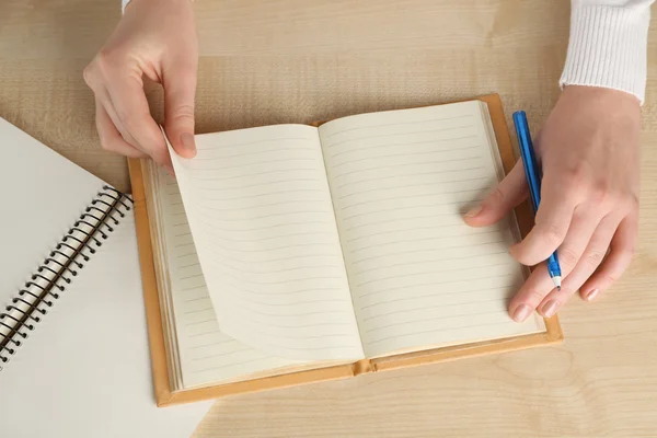 Vrouwelijke hand met pen en dagboek op houten tafel achtergrond — Stockfoto