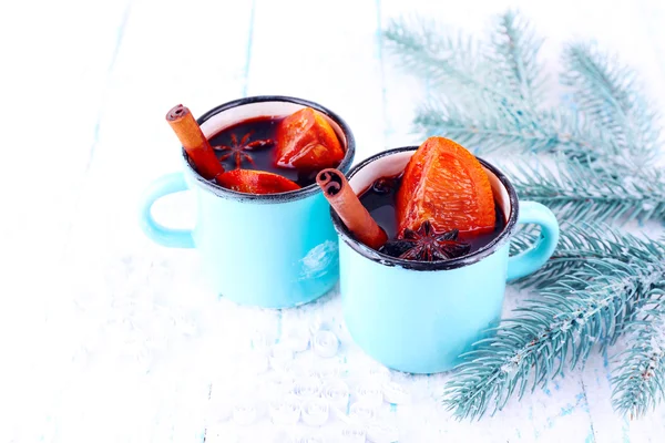 Tasses de vin chaud avec des morceaux d'orange et d'épices sur fond enneigé — Photo