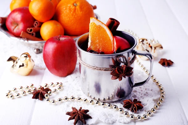 Tazza di metallo di vin brulè frutta, spezie e decorazioni natalizie su sfondo di legno a colori — Foto Stock