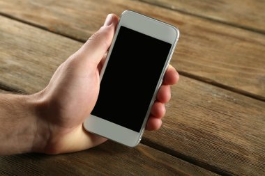 Akıllı cep telefonu ahşap masa arka planda tutan el
