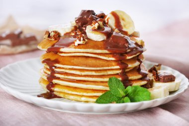 Nane, ceviz, çikolata ve ahşap plakalar arka plan üzerinde kumaş ile masada muz dilimleri ile krep yığını