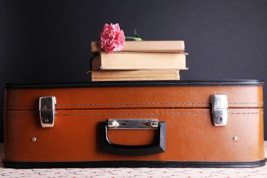 Vintage çanta ile yığın kitap desenli yüzey ve koyu arka plan üzerinde
