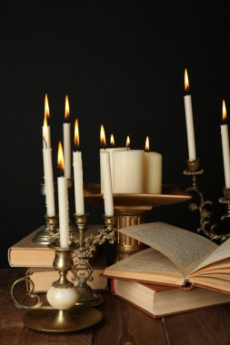 Mumlar ve kitaplar, siyah arka plan üzerine ahşap masa Retro şamdanlar