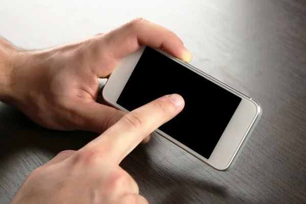 Hands holding smart mobile phone on wooden table background — Stock Photo, Image