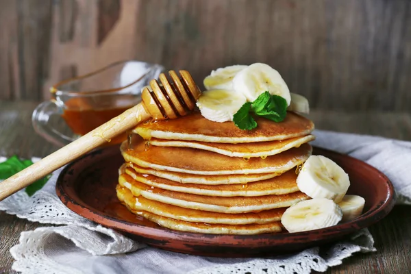 Tumpukan pancake dengan mint, madu dan irisan pisang di latar belakang kayu pedesaan — Stok Foto