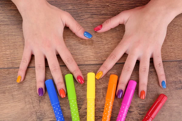 Multicolor female manicure with markers on wooden background — Stock Photo, Image