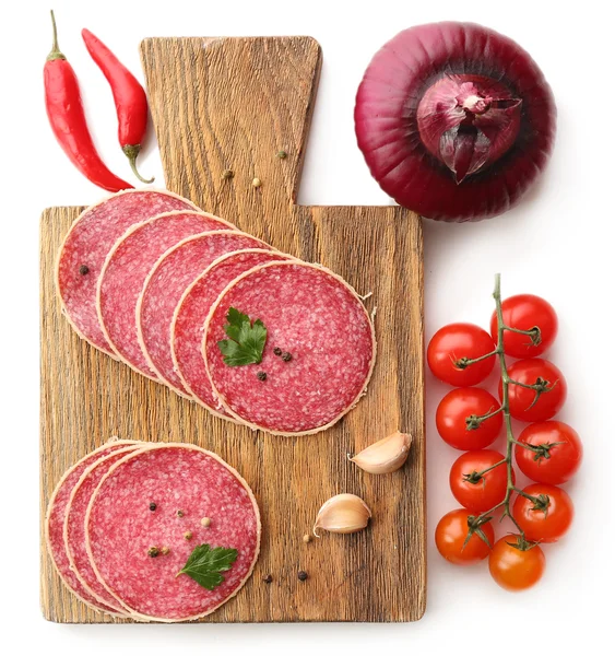 Rebanadas de salami con tomates cherry, chile, cebolla y especias en tabla de cortar de madera aislada en blanco — Foto de Stock