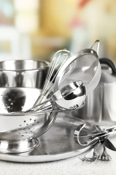 Stainless steel kitchenware on table, on light background — Stock Photo, Image