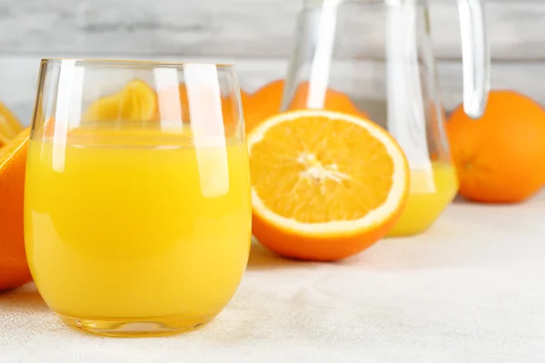 Glass of orange juice with slices on metal tray on table and color wooden wall background — Stock Photo, Image