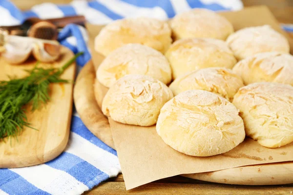 Bollos de pan frescos hechos en casa de masa de levadura y ajo fresco, eneldo en la tabla de cortar, sobre fondo de servilleta de color —  Fotos de Stock