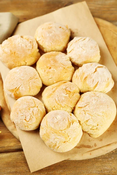 Verse zelfgemaakte brood broodjes van gistdeeg op houten bord, op een servet achtergrond kleur — Stockfoto