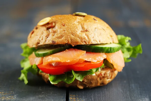 Sandwich with salmon on wooden background — Stock Photo, Image