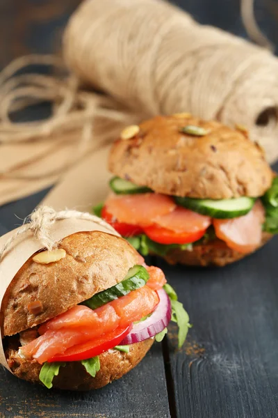 Sandwiches with salmon and vegetables on wooden background — Stock Photo, Image