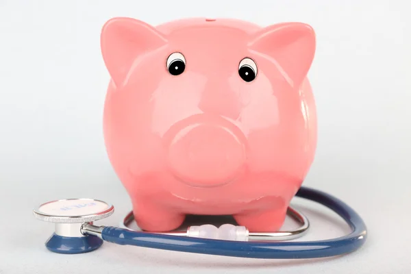 Pink piggy bank with stethoscope isolated on white — Stock Photo, Image