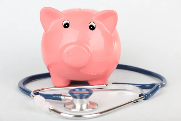 Pink piggy bank with stethoscope isolated on white — Stock Photo, Image